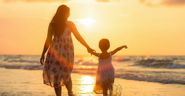Mother and daughter walking on a sunny beach