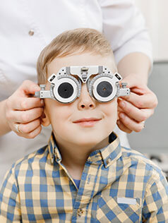 A blond kid smiling getting a pediatric eye health exam