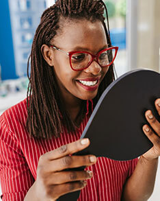 Woman wearing eyeglasses while looking at the mirror