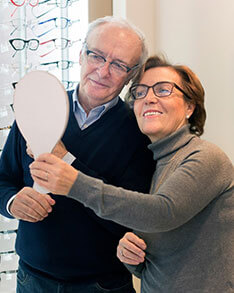 Elderly couple looking at mirror wearing glasses from Bard Optical Peoria Metro Centre
