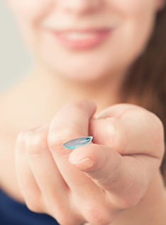 Woman holding contact lenses with her fingertip