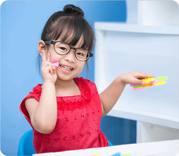 Little asian girl wearing glasses playing with toy blocks