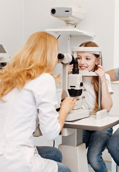 A blond kid smiling getting a pediatric eye health exam in Bard Optical Quincy